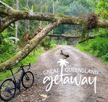 A photo of an e-gravel bike in the rainforest, with the logo for the Great Queensland Getaway promotion