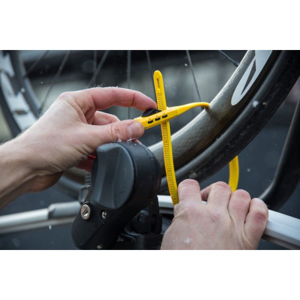 A photo of a person attaching the Hiplok Z lock to their bike, securing it to a car. 