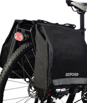 A photo of the double pannier on the back rack of a bike. The pannier bag has straps for the top of the rack, and straps near the bottom to secure it to the bike completely
