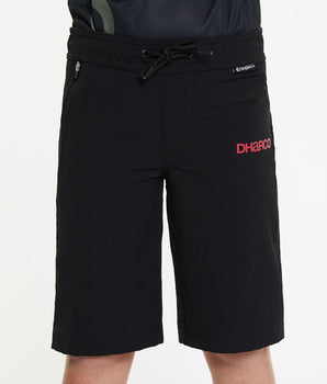 A close up photo of the young rider wearing the Black Youth Gravity Shorts, showing the drawstring waistband, zip up pockets, and a red DHaRCO logo printed on the hips. The shorts are designed to come down to the rider's knees.