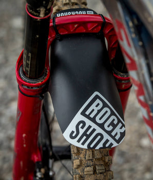 A photo of the black and white Rockshox Mudguard Fender on a mud-caked mountain bike