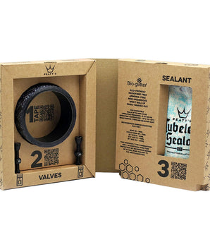 A photo of the inside of the box, showing the tape, valves, and tubeless sealant included in the kit, as well as including QR codes for the instructions.